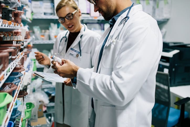 Two chemist working in pharmacy drugstore. Male and female pharmacists checking inventory at pharmacy.