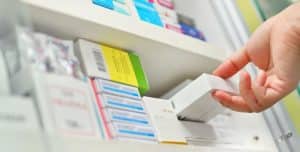 Closeup pharmacist hand holding medicine box in pharmacy SCAIR blog