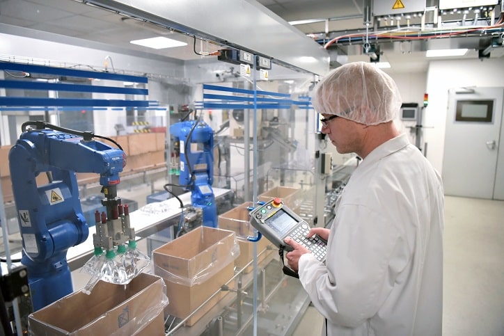 Conveyor belt worker operates a robot that transports insulin bags - modern factory for the production of medicines in the healthcare sector