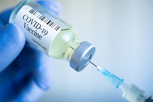 A syringe extracting covid-19 vaccine from a vial.