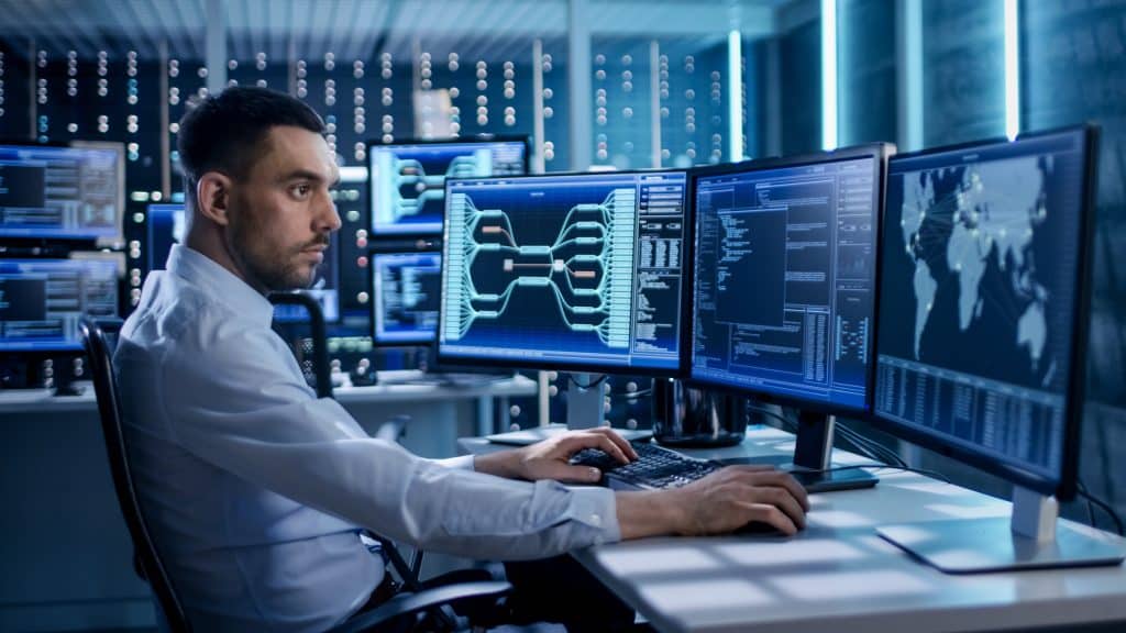 Supply chain cyber security concept - security engineer working in front of multiple screens.