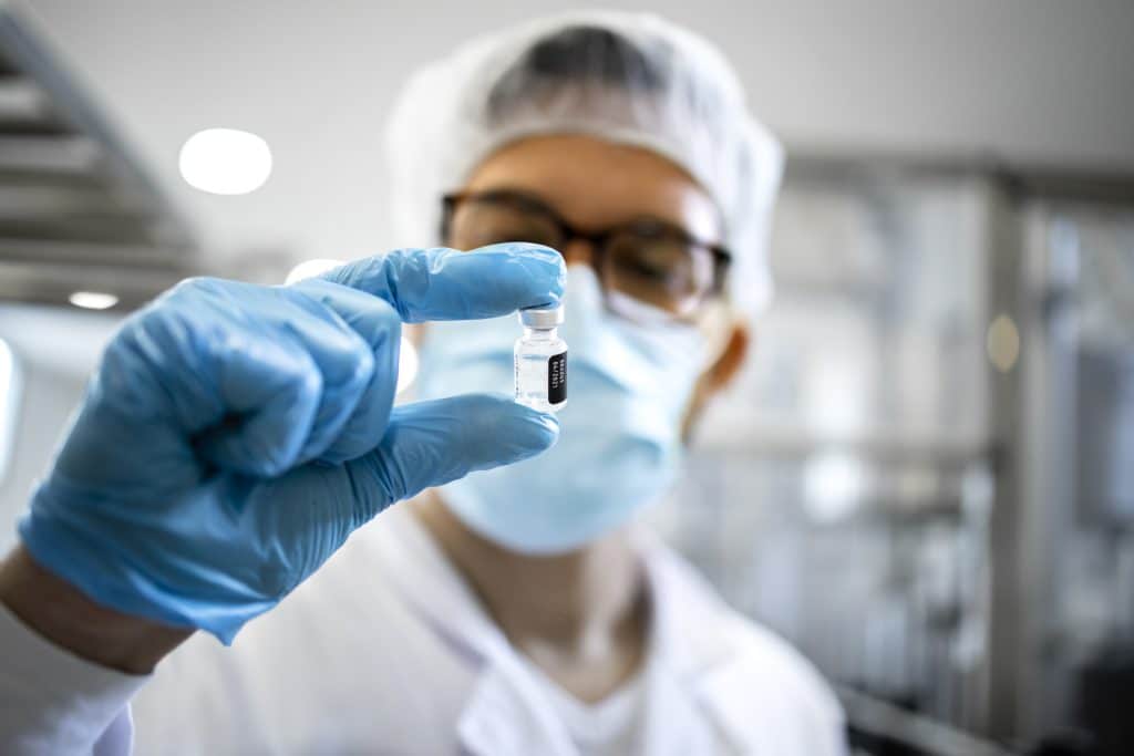 Pharma worker holding vial of medicine in factory