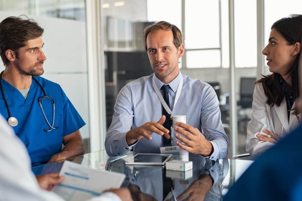 Pharmaceutical advisor showing new medicine to doctors