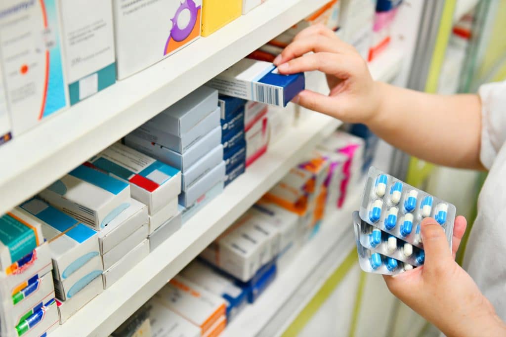 Close up of pharmacist's hands holding medicine pills on shelf. Concept for new MAPS supply chain transparency act.